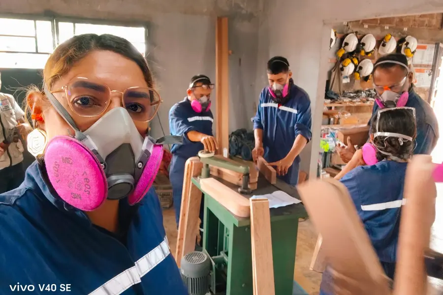 Una aprendiz con protección respiratoria opera una máquina del taller